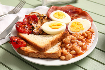Plate of tasty English breakfast with boiled eggs on green wooden background