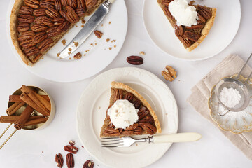 Plates with pieces of tasty pecan pie on white background