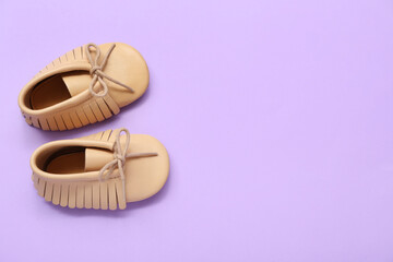 Pair of stylish baby booties on lilac background
