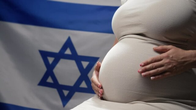 Unrecognizable future mother expecting baby on Israeli national flag background. Pregnant woman touching belly. Demography, jewish population in Israel
