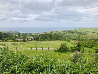 landscape of fields and rolling hills in British countryside and sea in the distance on a cloudy day