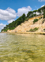Obraz premium seascape of island rocky cliffs taken from kayak with white fluffy clouds and blue sky