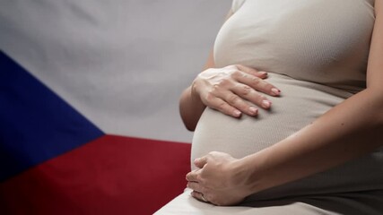 Unrecognizable future mother expecting baby on Czech Republic national flag background. Pregnant woman touching belly. Demography, population in Czechia