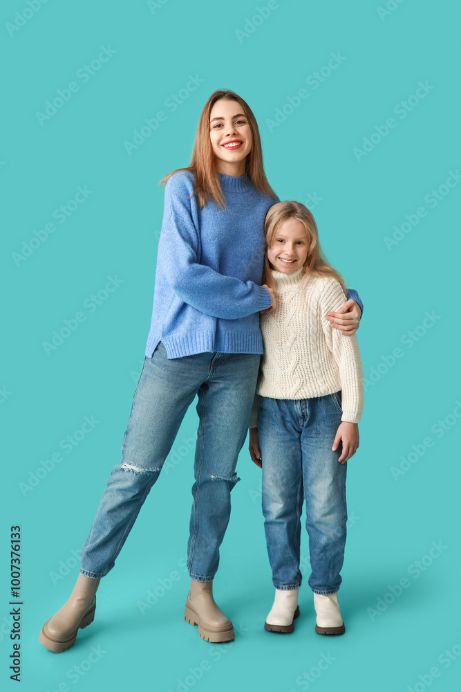 Wall mural Cute little girl and her mother in winter clothes on blue background