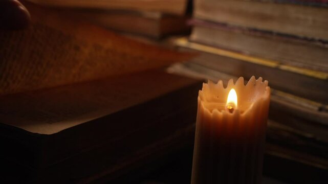Man reading old book under wax candlelight in library. Middle-ages authentic cozy room. Candle burning. Literature promotions or tranquil visual storytelling