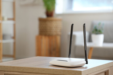 Modern wi-fi router on wooden table in living room, closeup