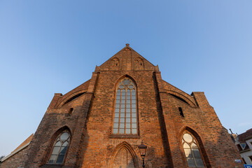 Looking up at front exterior facade of former church now library against a clear blue sky
