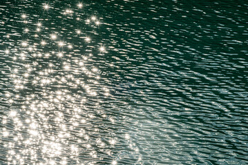 Stunning water shimmering on with sun reflecting on the service with turquoise, green body of liquid for background, wallpaper, desktop photo. 