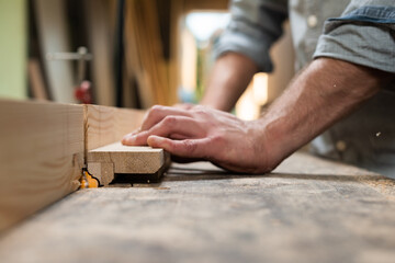 A carpenter mills an oak part with a milling cutter by hands
