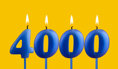 Blue birthday candle on yellow background - Number 4000