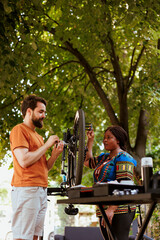 Multiethnic couple checking and repairing bicycle tire with work tools in yard for summer cycling....