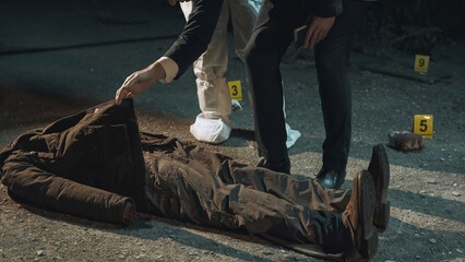 Detective arriving at crime scene and receiving report from forensic scientist, while the rest of the experts collect evidence next to headless body. Night scene.