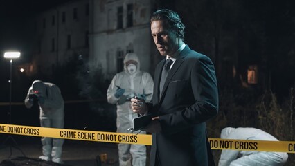 Detective inspecting area and smoking at crime scene at night as forensic experts collect evidence...