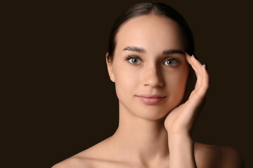 Young woman with beautiful eyebrows on dark background