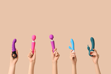 Female hands with different vibrators on brown background