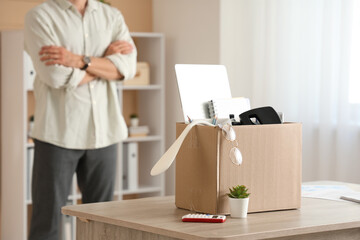 Fototapeta premium Fired young man with box of personal stuff in office, closeup