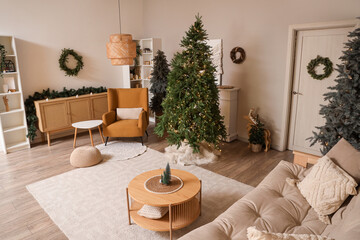 Interior of living room with table, sofa and Christmas trees near light wall