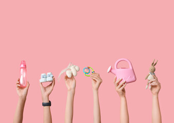 Female hands with baby toys and accessories on pink background