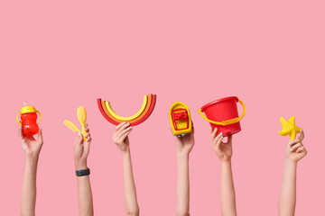 Female hands with baby accessories and toys on pink background