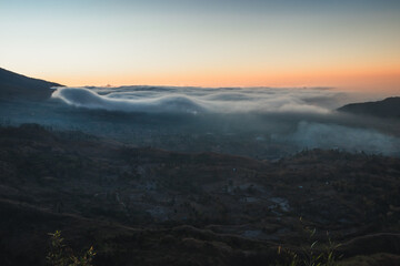 Clouds in a mountain valley at sunset.