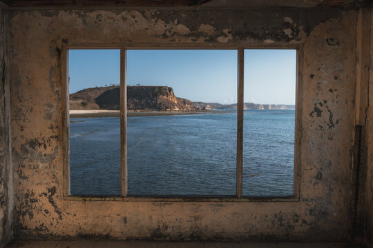 Fototapeta A look through an old window out to see from an abandoned house.