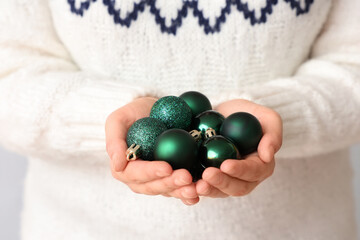 Woman in stylish warm sweater with beautiful Christmas balls, closeup