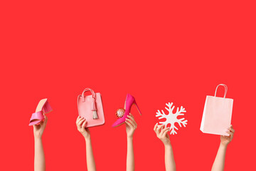 Many female hands with shoes, decorative snowflake and shopping bag on red background