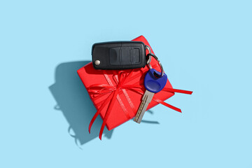 Gift box and keys of new car on color background