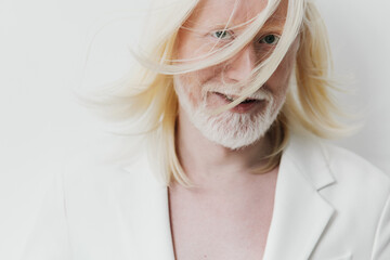 Portrait of a man with long white hair and a beard, wearing a white suit against a plain white background, conveying elegance and uniqueness