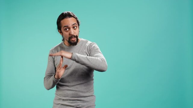 Portrait of assertive man asking for timeout, doing hand gestures, feeling fatigued. Unhappy person doing vehement pause sign gesturing, wishing for break, studio background, camera B