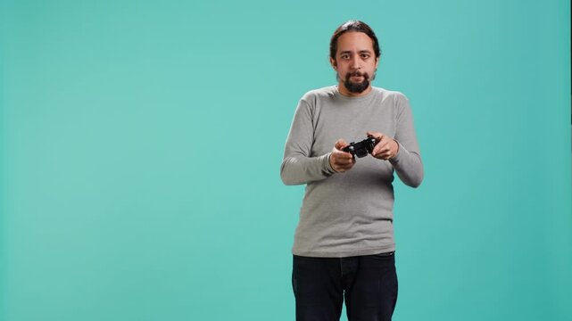 Portrait of gamer annoyed after losing online multiplayer videogame, being defeated by rival players. Man upset after seeing game over message, holding controller, studio background, camera A