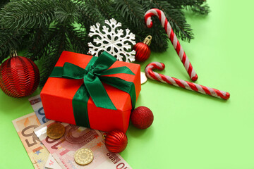 Composition with Christmas gift, money and decorations on green background