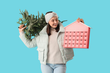Young woman with Christmas tree and advent calendar on blue background