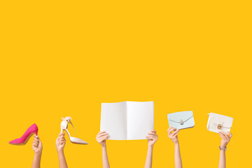 Female hands with blank magazine, stylish bags and high heels on yellow background