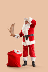 Santa Claus with Christmas bag and moose antler looking on beige background
