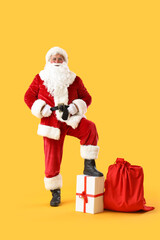 Santa Claus with bag and Christmas gift box on yellow background
