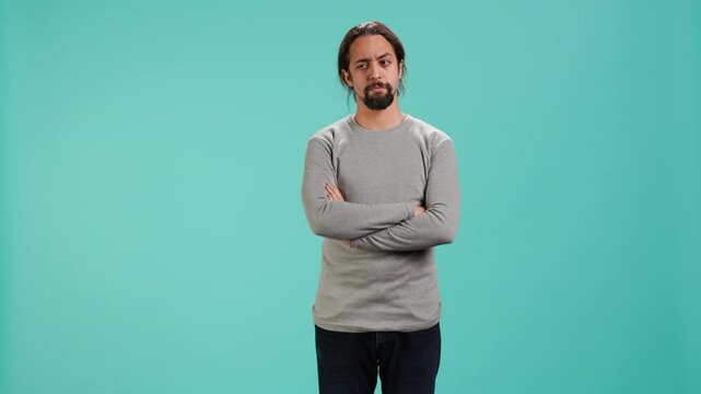 Grumpy man crossing arms, feeling upset by events, isolated over studio background. Portrait of stressed moody person shaking head, left speechless by troubling news, camera A