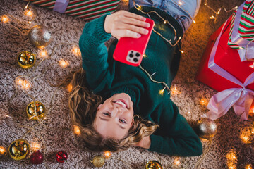 Photo of attractive teen girl lying floor device dressed green christmas outfit cozy day light home...