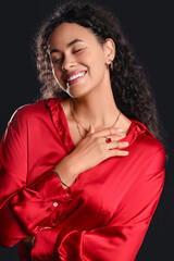 Beautiful young happy African-American woman with stylish jewellery on black background