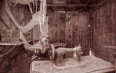 An abandoned antique sewing machine sits in a dilapidated wooden shack at Bodie State Historical Park, California. Cobwebs and dust create an eerie atmosphere in this preserved ghost town.