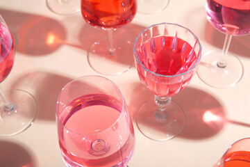 Glasses of tasty pink wine on beige background