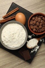 Flour, chocolate and other ingredients for making dough on wooden table, top view
