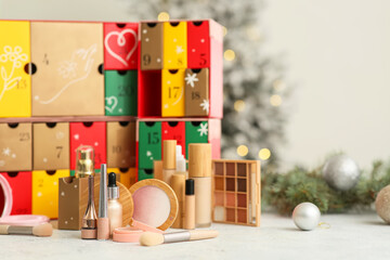 Makeup products with Christmas Advent calendar on table against blurred lights, closeup