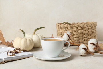 Cup of tasty pumpkin coffee with autumn decorations and jewellery on white grunge background