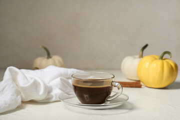 Cup of tasty pumpkin coffee with autumn decorations on grunge white background