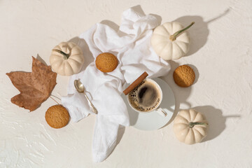 Cup of tasty pumpkin coffee with autumn decorations and cookies on grunge white background
