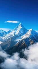 Fototapeta premium Spectacular snowy mountain peak against a clear blue sky, surrounded by fluffy clouds.