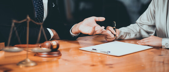 Professional business meeting with a lawyer discussing legal documents and signing a contract at a wooden desk.