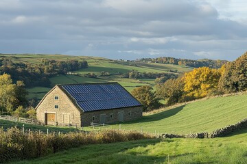 Obraz premium A stone barn with solar panels on the roof sits on a green hillside with autumnal foliage.