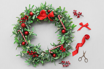Christmas mistletoe wreath with beautiful decorations and scissors on grey background